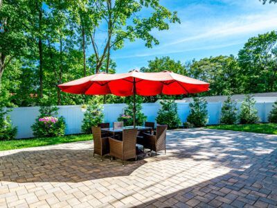 A patio with a table and chairs under a red umbrella.