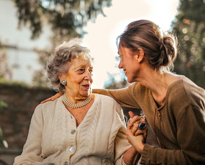 A young woman is talking to an older woman in a wheelchair.