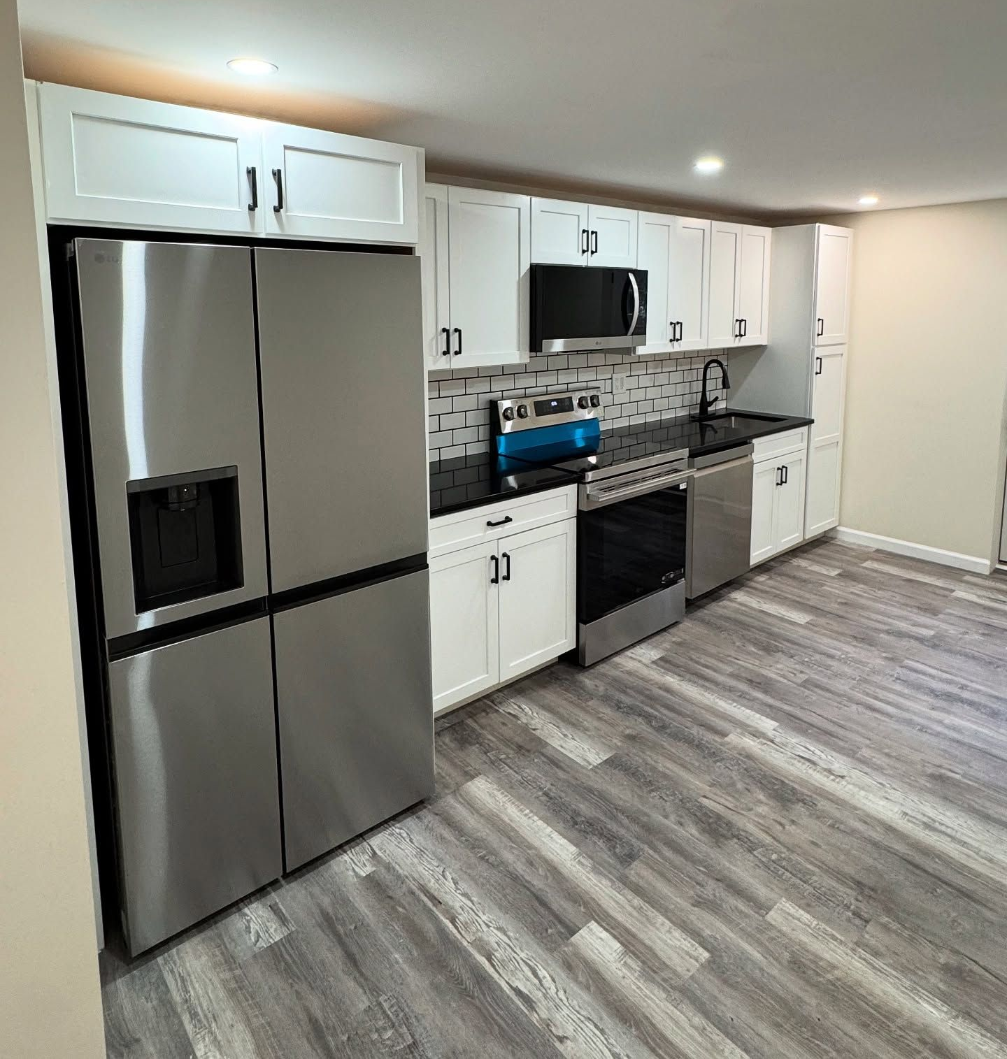 Modern kitchen remodel completed with white cabinets, stainless steel appliances, and new flooring.