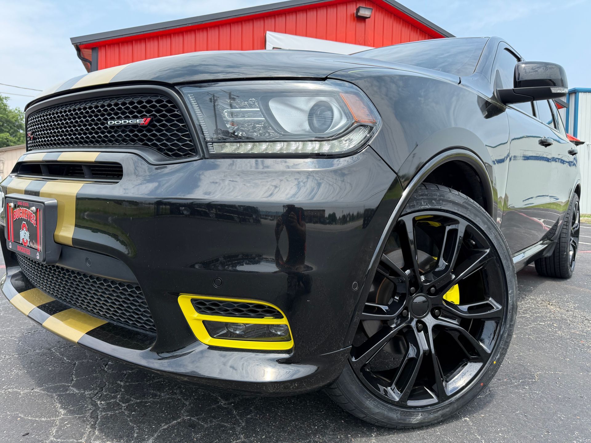 A black and yellow dodge durango is parked in front of a red barn.
