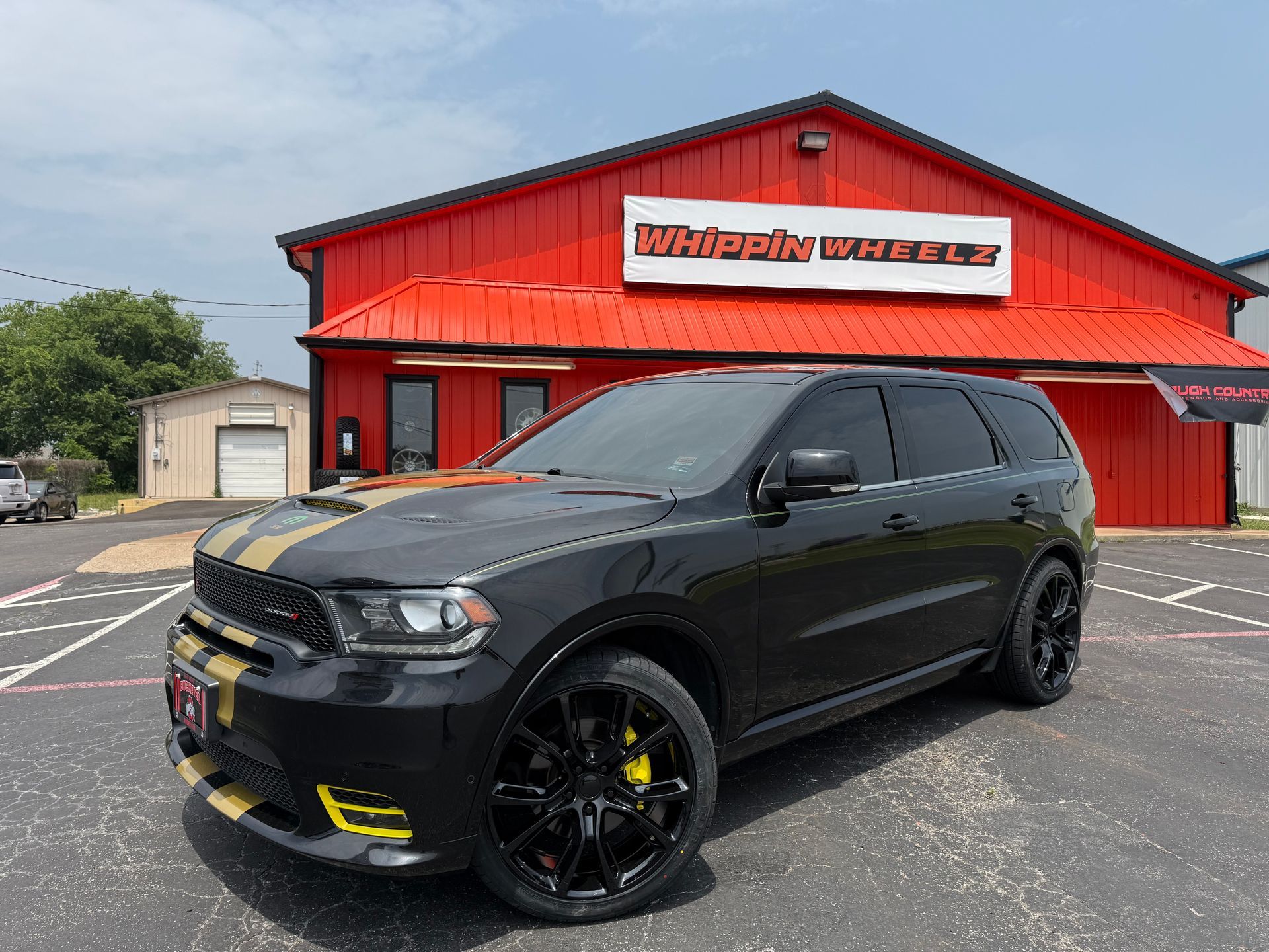A black dodge durango is parked in front of a red building.