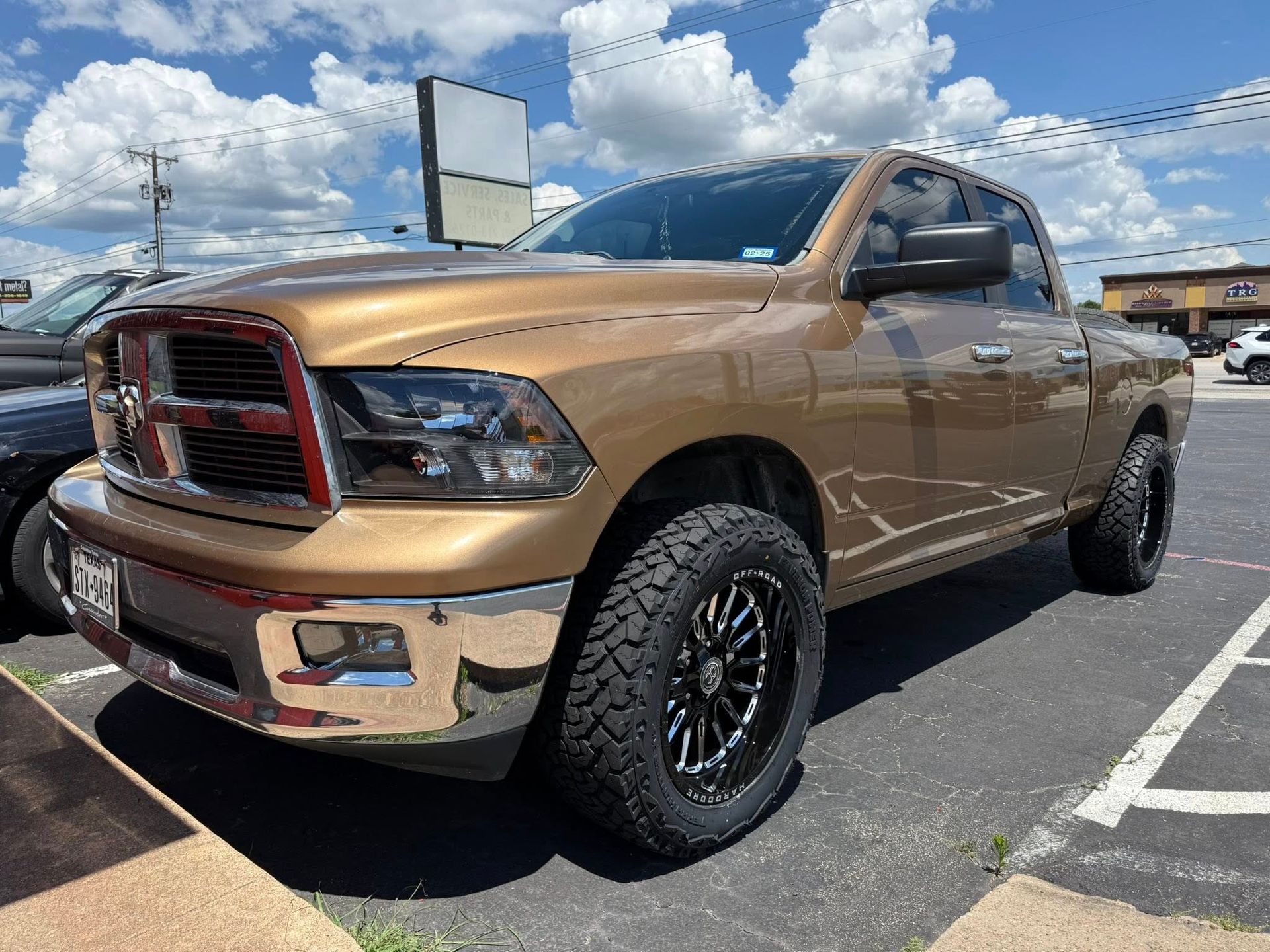 A gold dodge ram truck is parked in a parking lot.