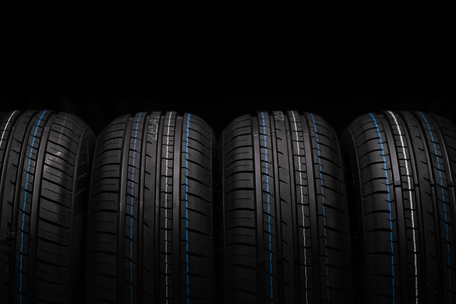 A row of black tires with blue stripes on a black background.