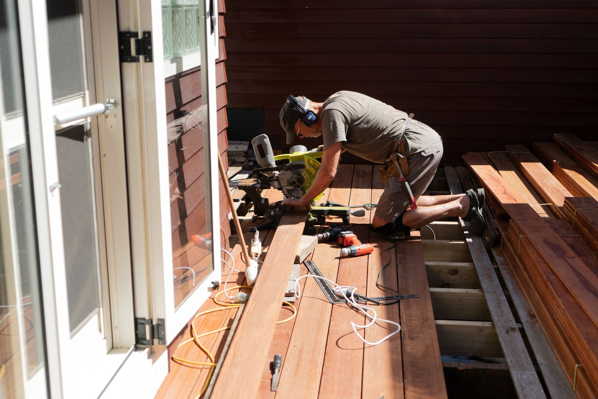 A man is working on a wooden deck with a saw
