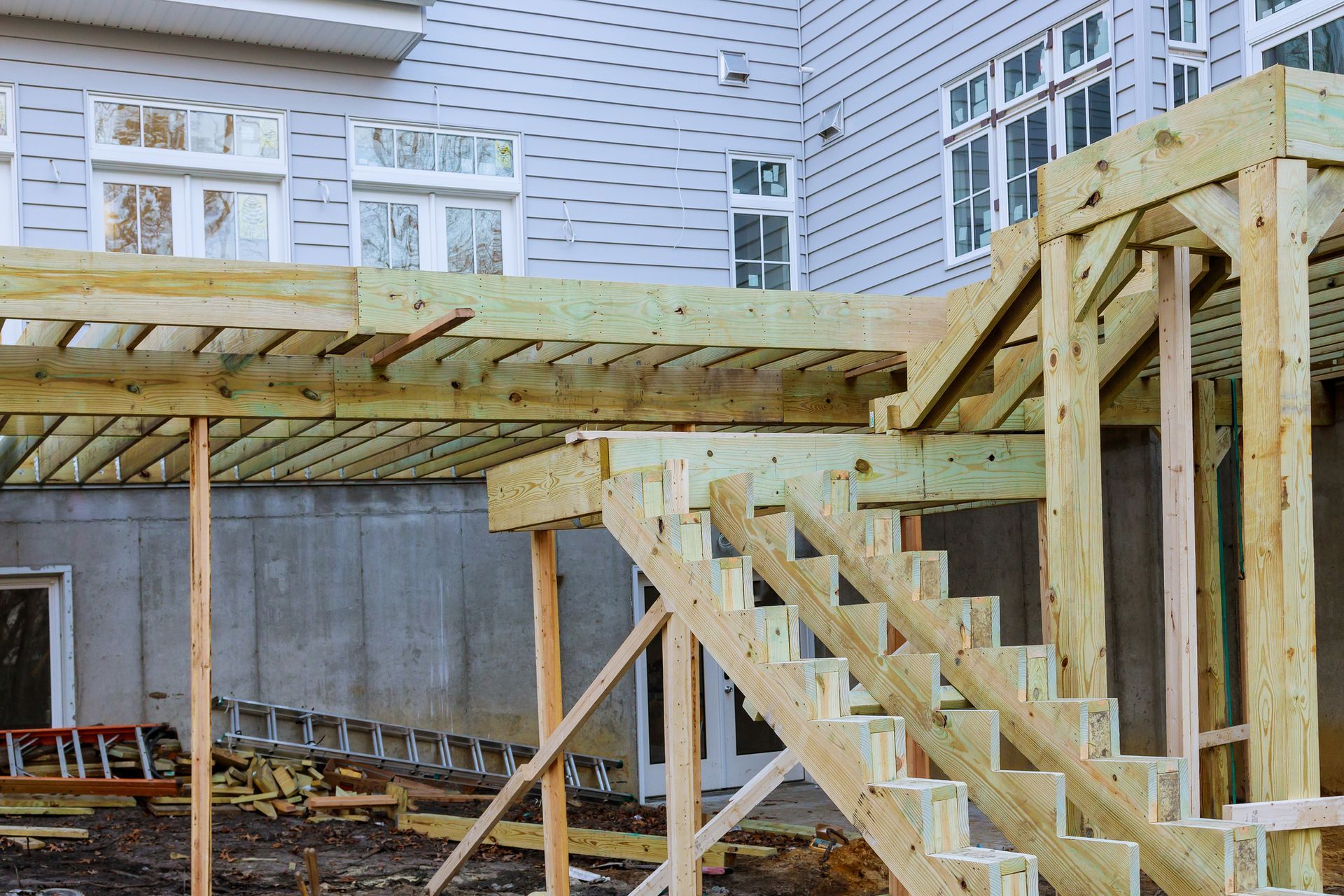 New wooden deck and staircase construction in progress at the back of a modern residential house.