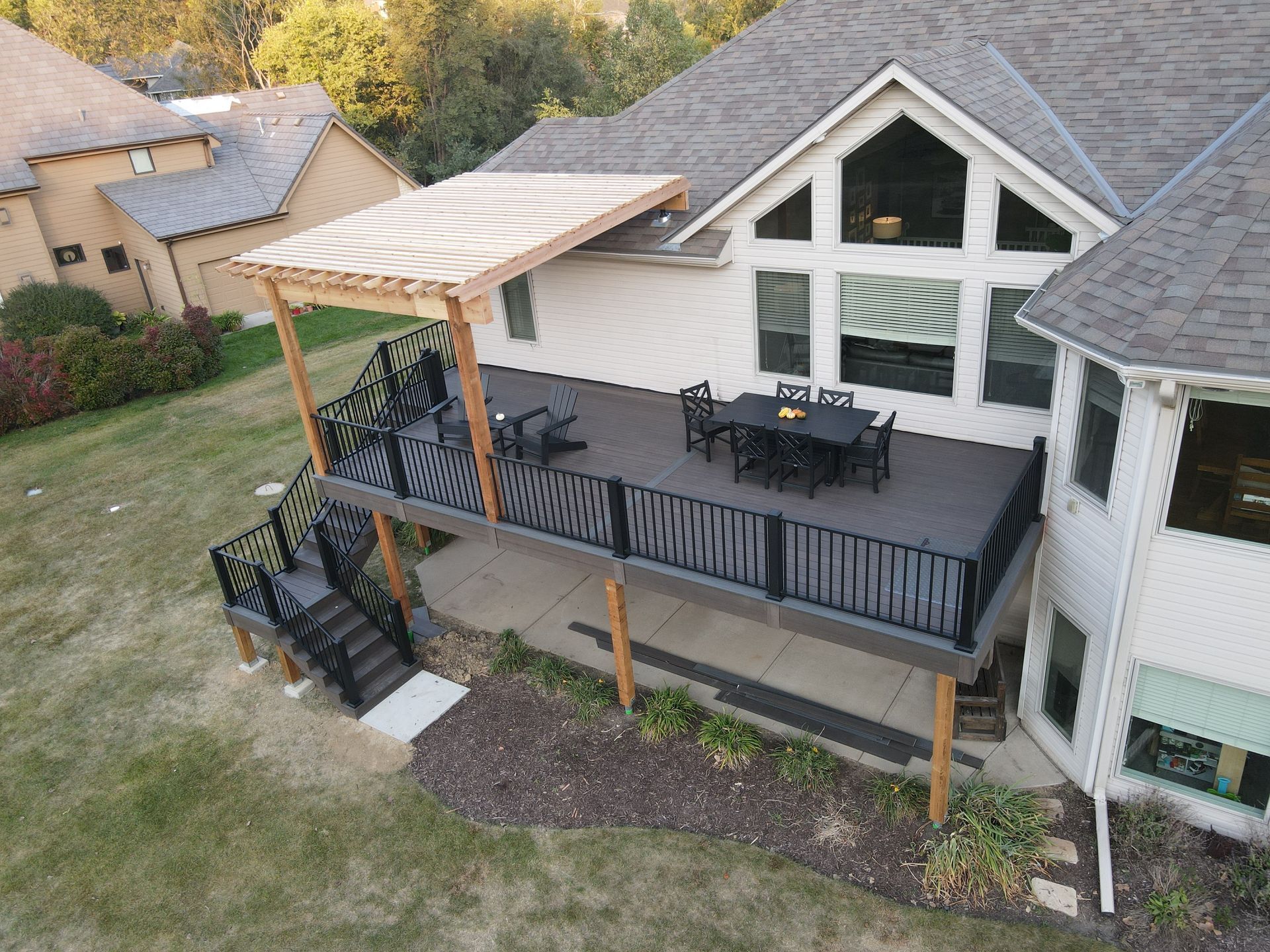 An aerial view of a house with a large deck and a pergola.