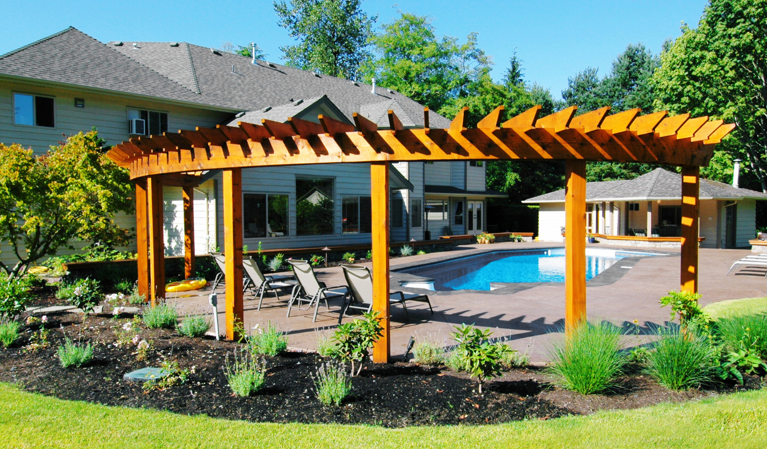 Backyard design with custom pool, patio and hardscape design and lovely wood pergola.