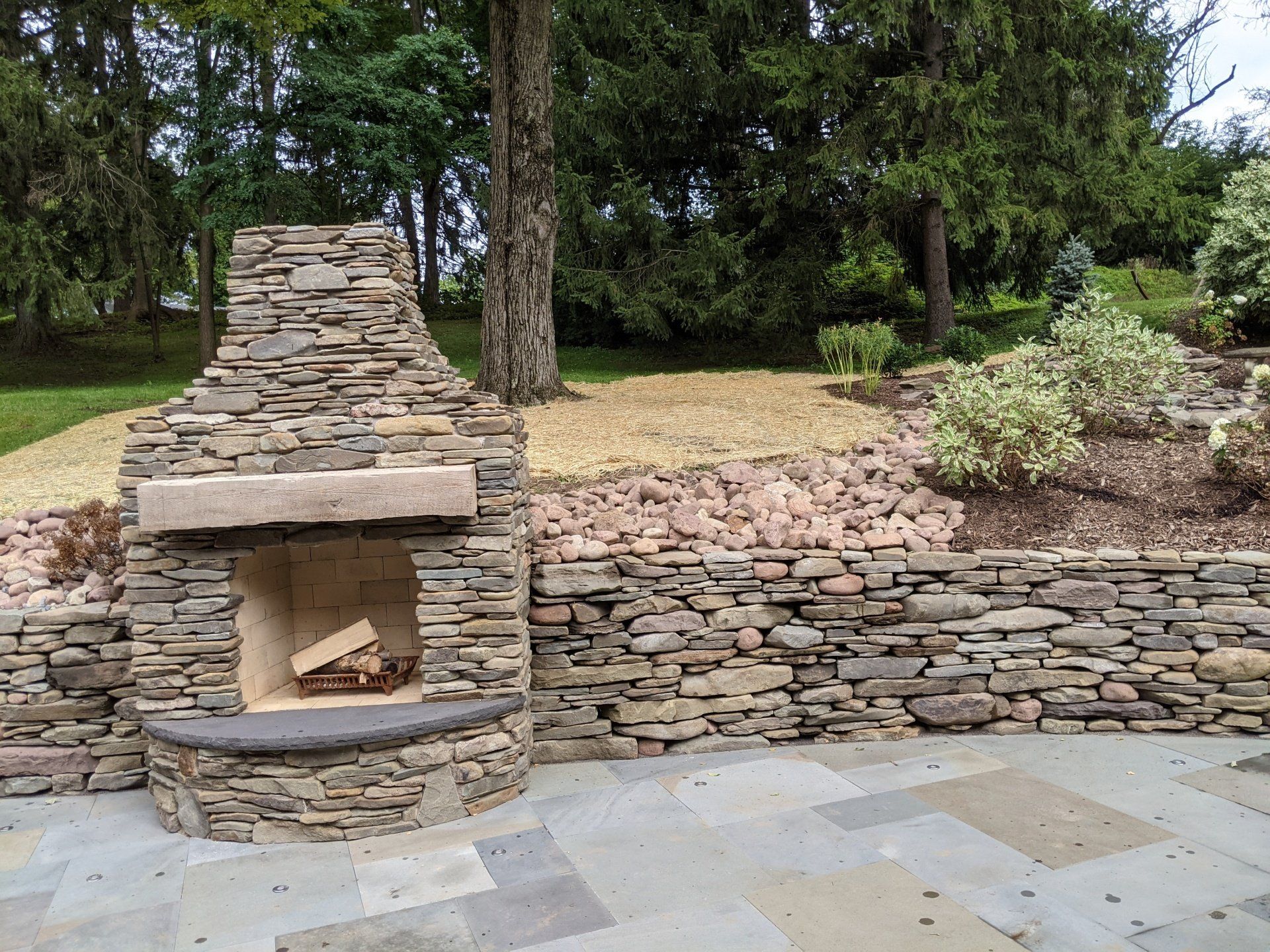 a stone fireplace is sitting on a patio next to a stone wall .