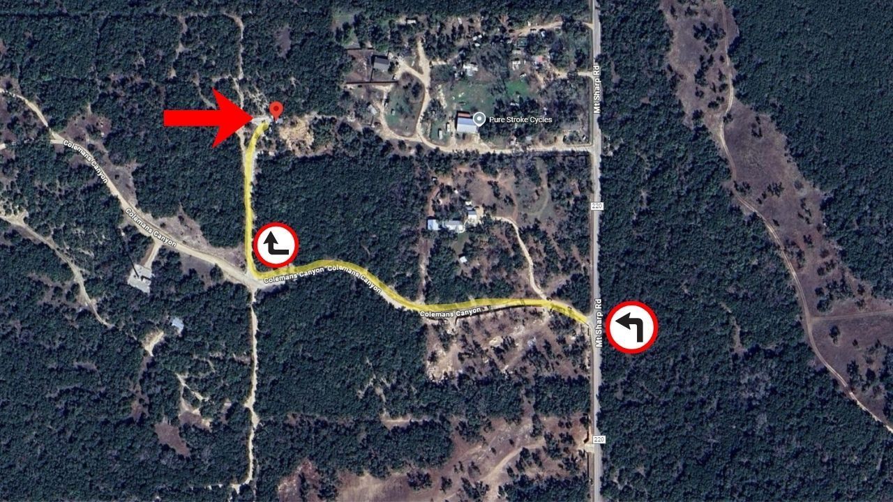 Overhead view of a rural road with a marked route leading to a building, a left turn sign, and a yield sign.