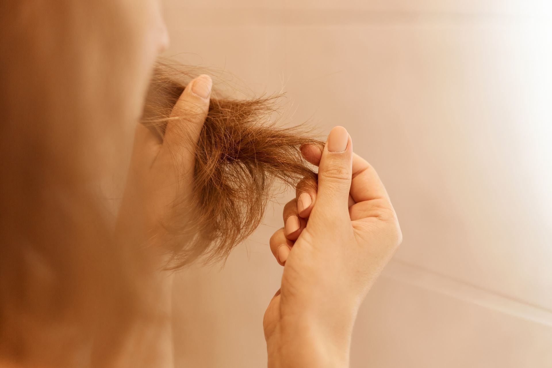 Mulher analisando o cabelo para saber se precisa lavar