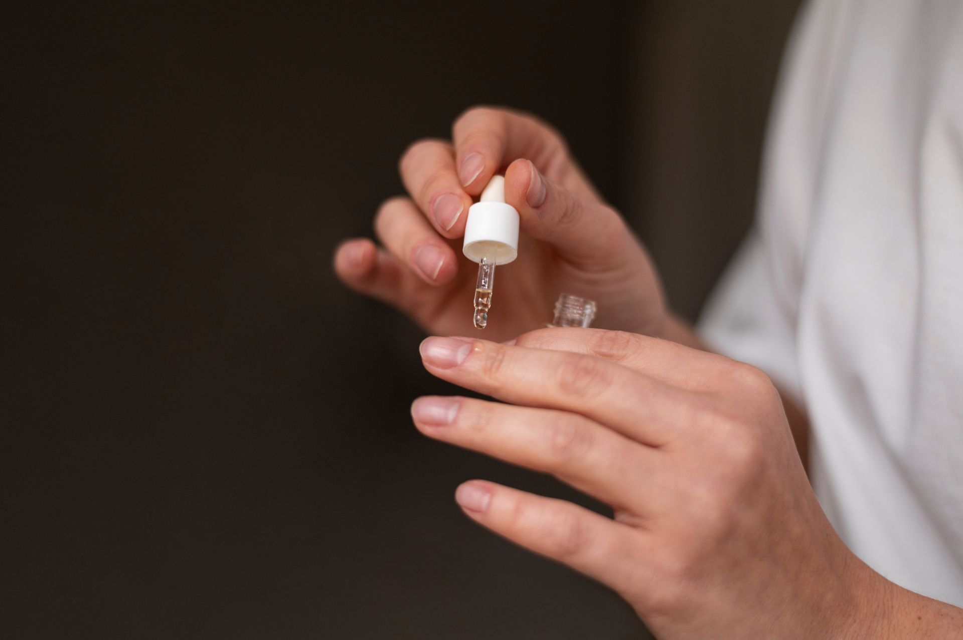 Mulher aplicando óleo fortalecedor nas unhas para tratamento e hidratação