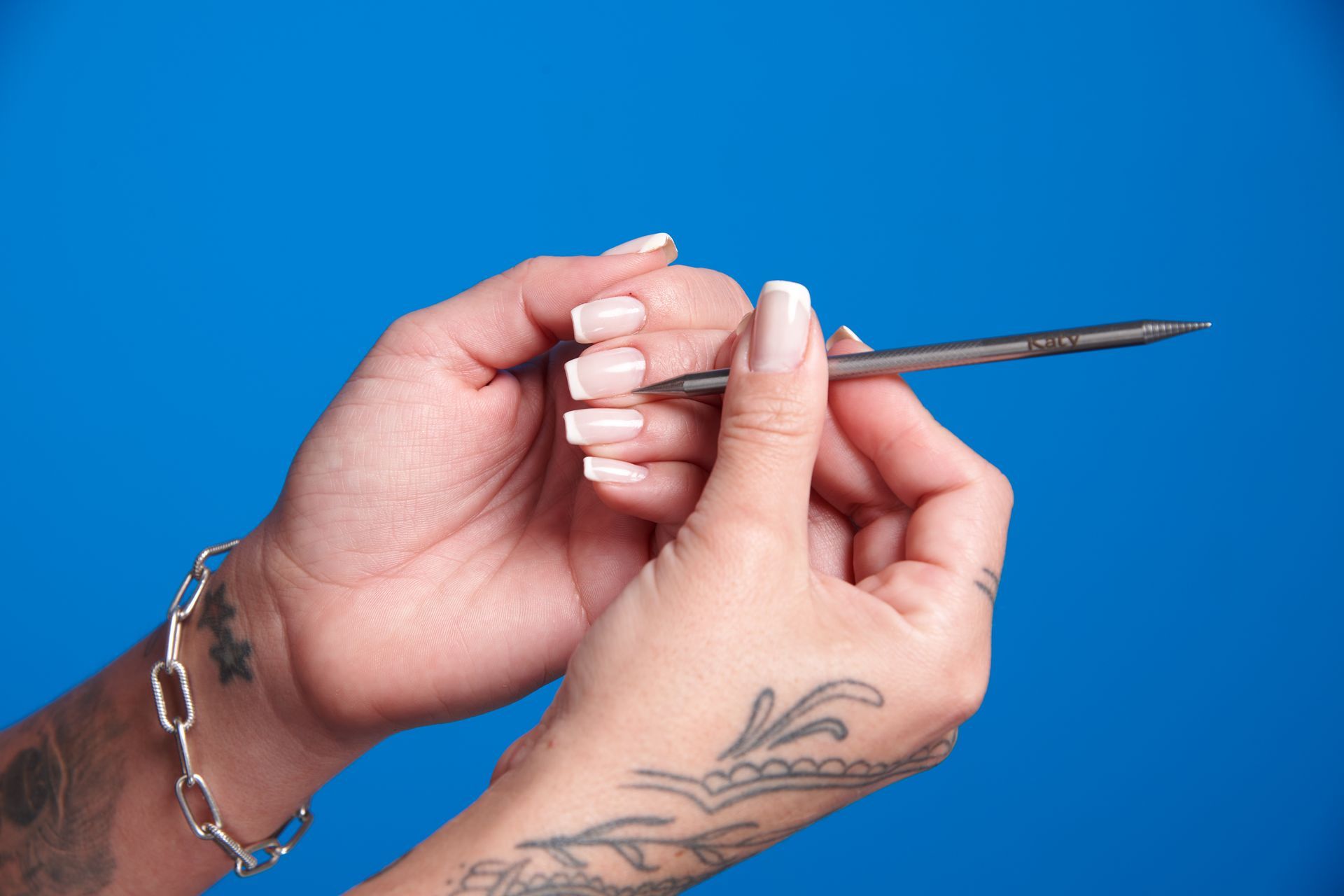 Mulher fazendo própria unha em casa usando palito de unha inox Katy para limpar e afastar cutículas.