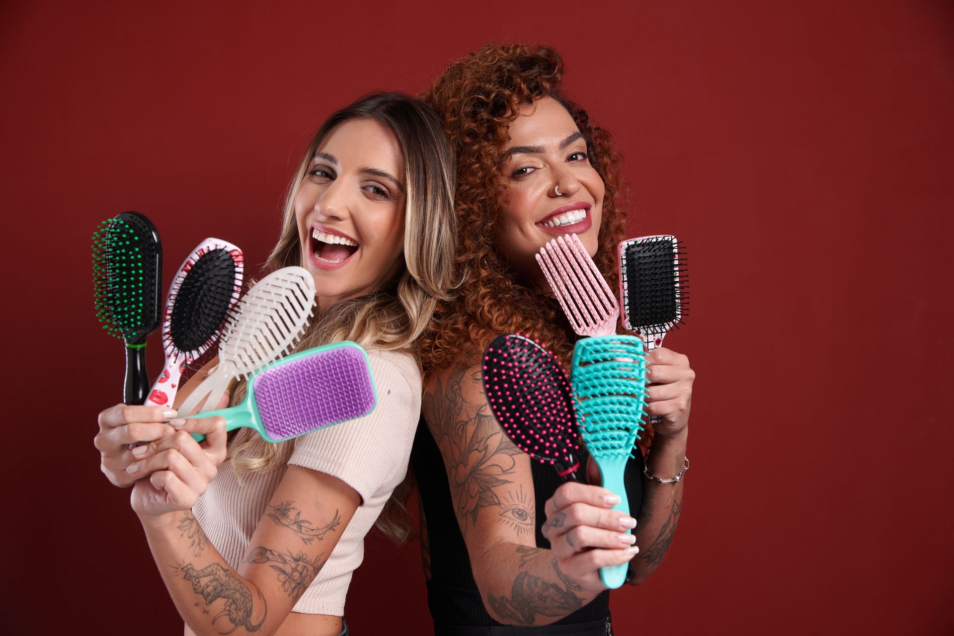 Duas mulheres sorridentes segurando escovas de cabelo Katy em diferentes modelos.