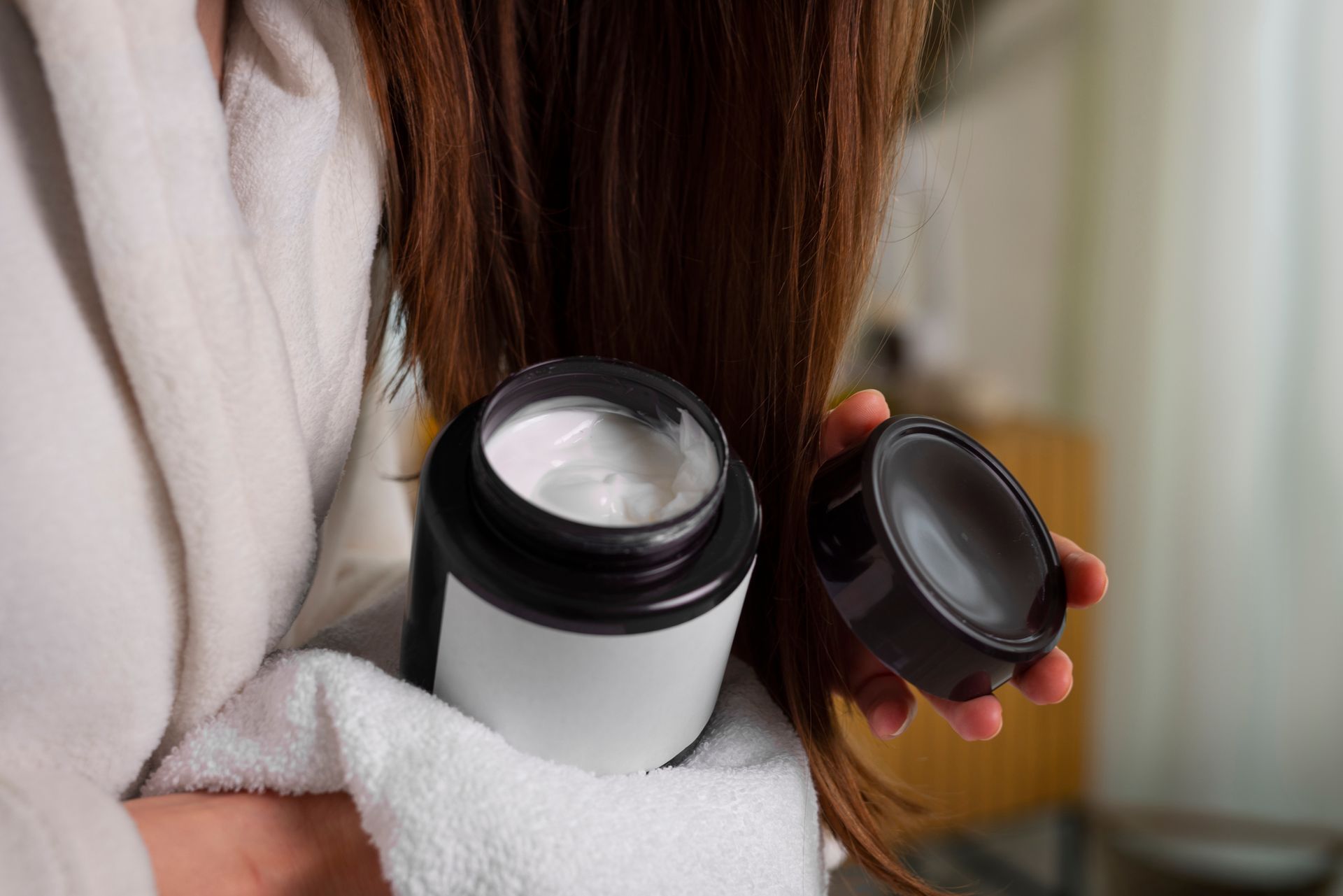 Mulher aplicando máscara de tratamento no cabelo durante rotina de cuidados