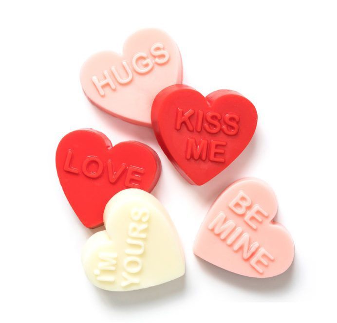 a group of candy hearts that say hugs kiss me and be mine