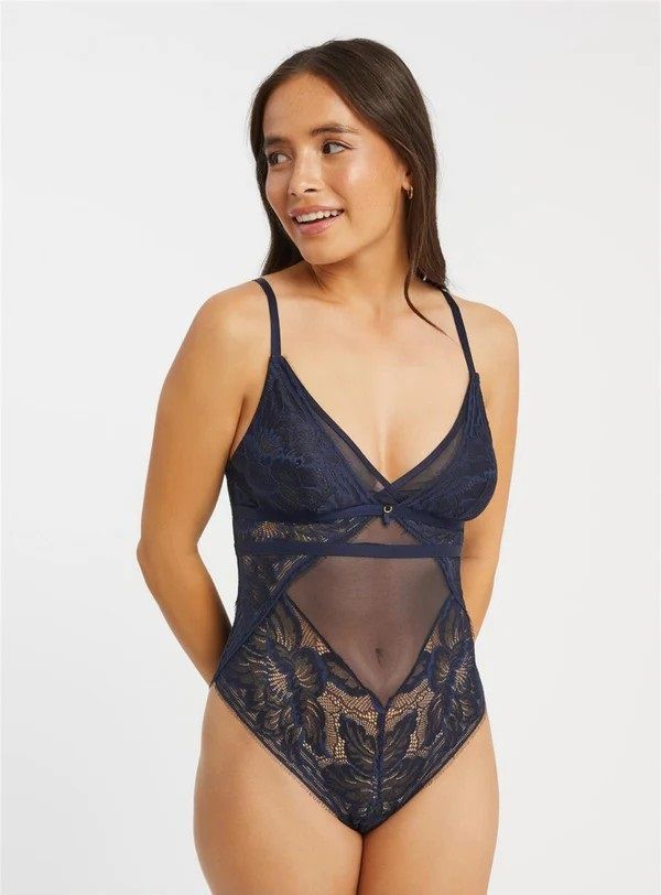 a woman in a black bodysuit is standing in front of a wall