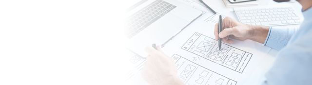 A man is drawing on a piece of paper with a pen.