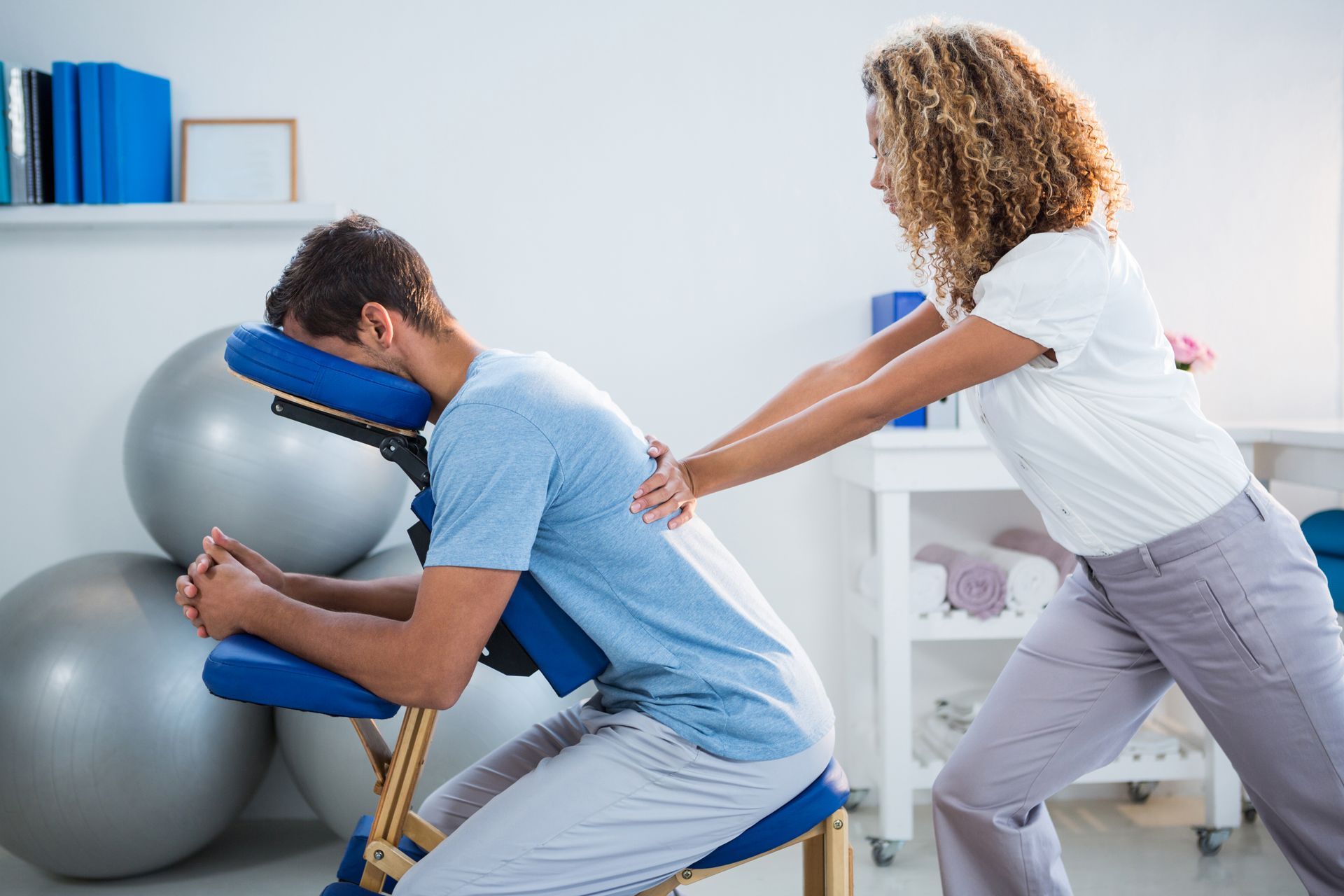 A woman is giving a man a massage in a chair.
