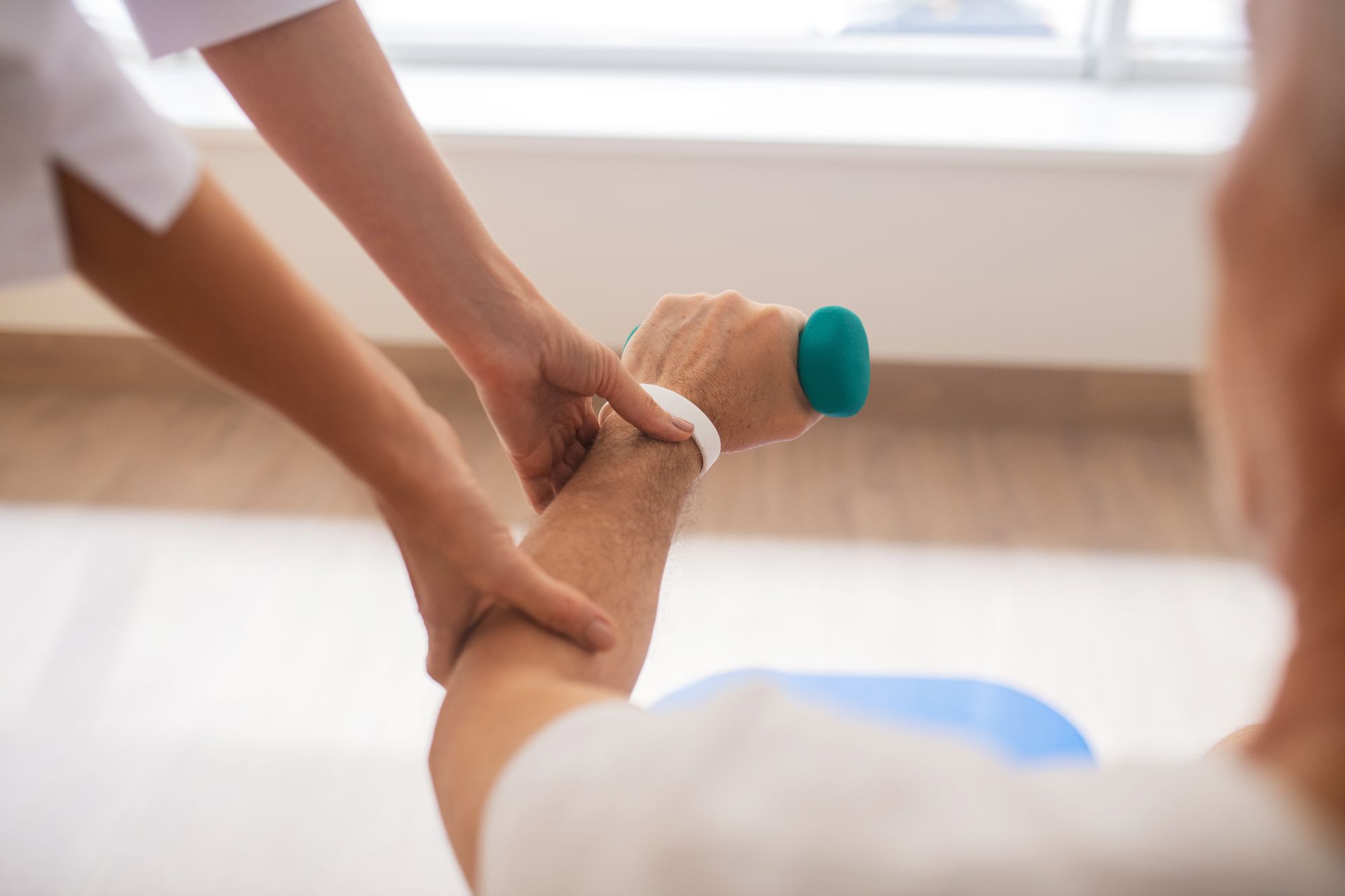 Therapist assisting patient with arm exercise using a green dumbbell; light setting.