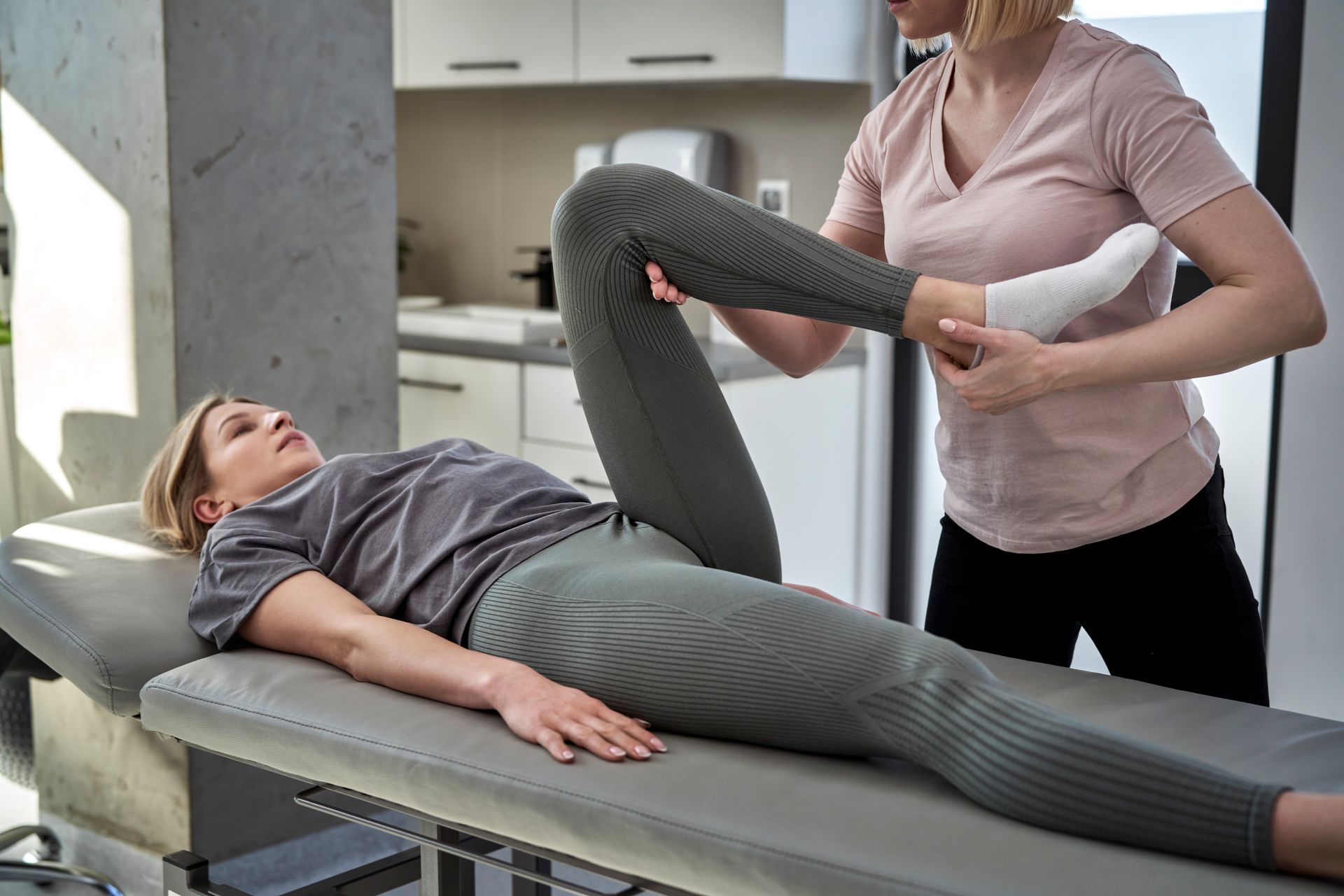 Woman receiving physical therapy for her leg from a therapist in a clinic.
