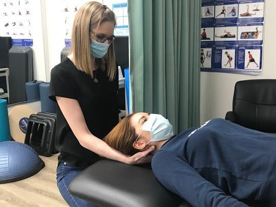 A woman wearing a mask is giving a man a massage.