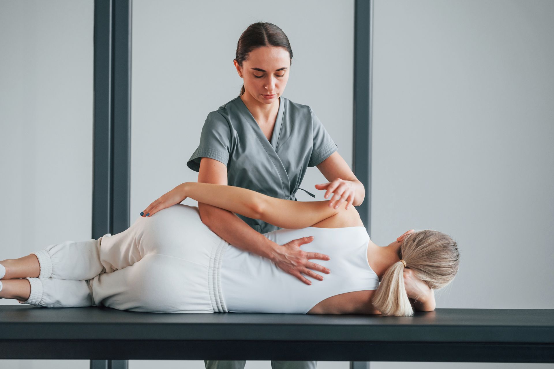 Woman receiving shoulder therapy from a therapist in a clinic.