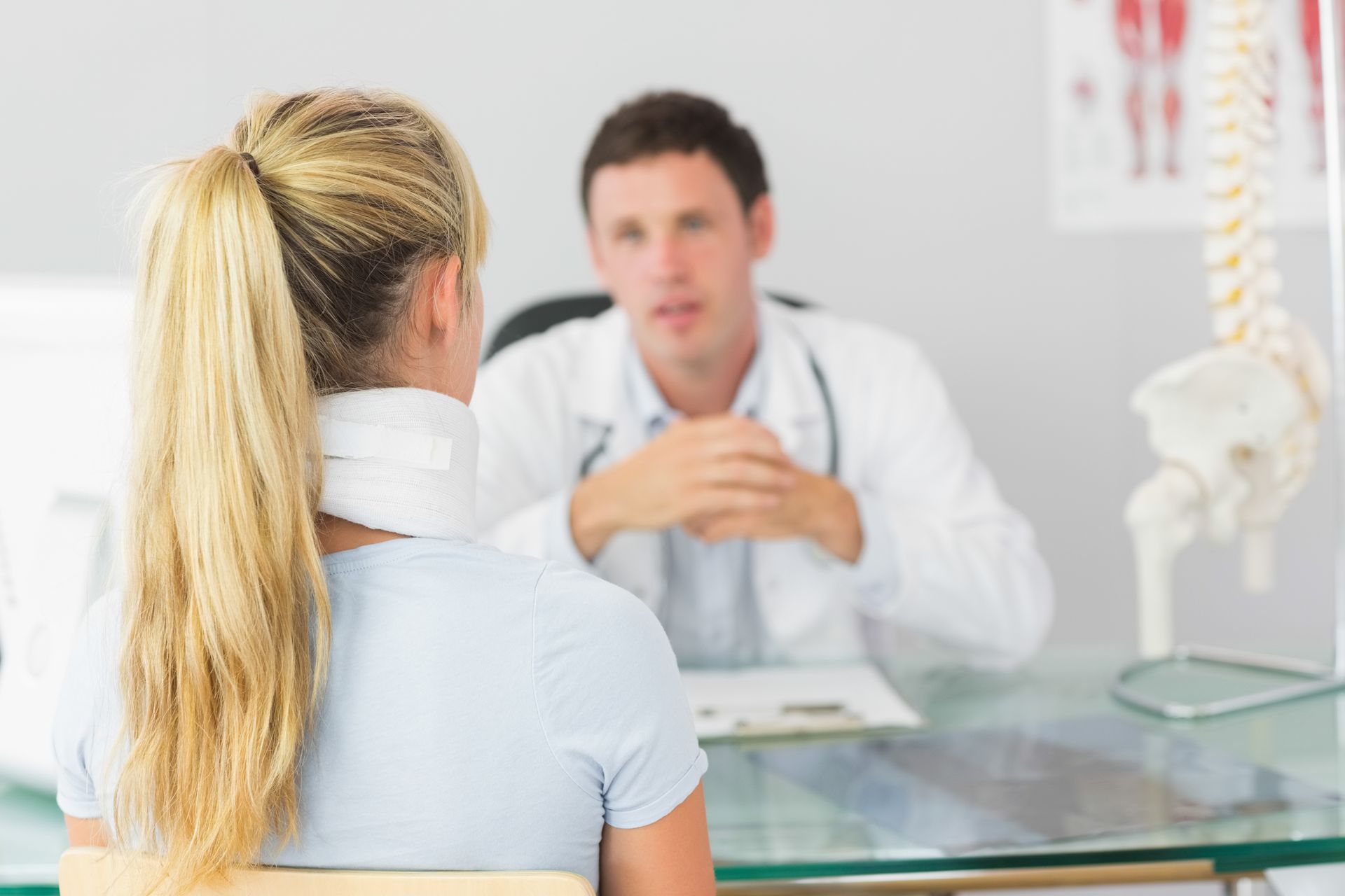 A woman with a neck brace is talking to a doctor.