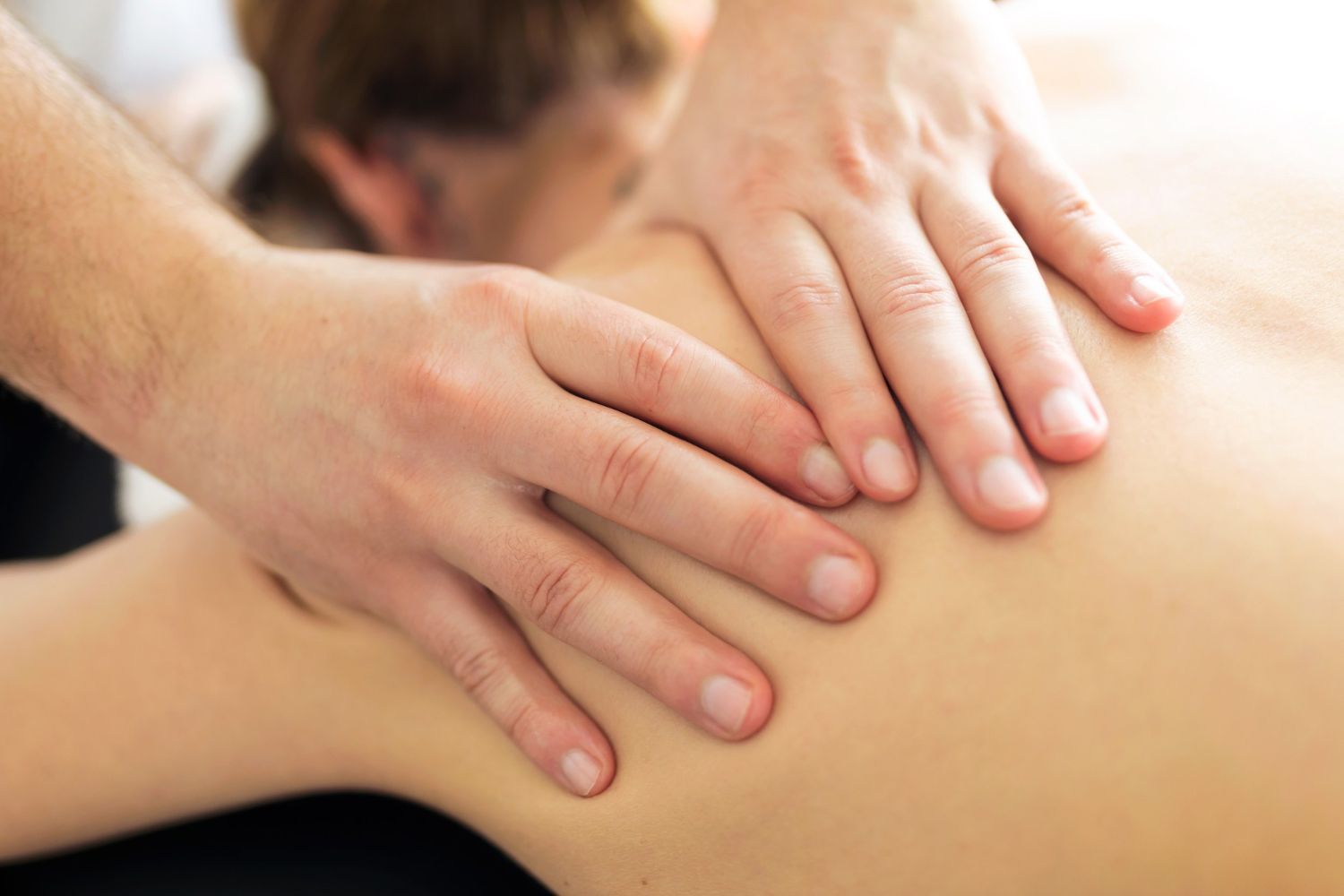 A man is giving a woman a massage on her back.