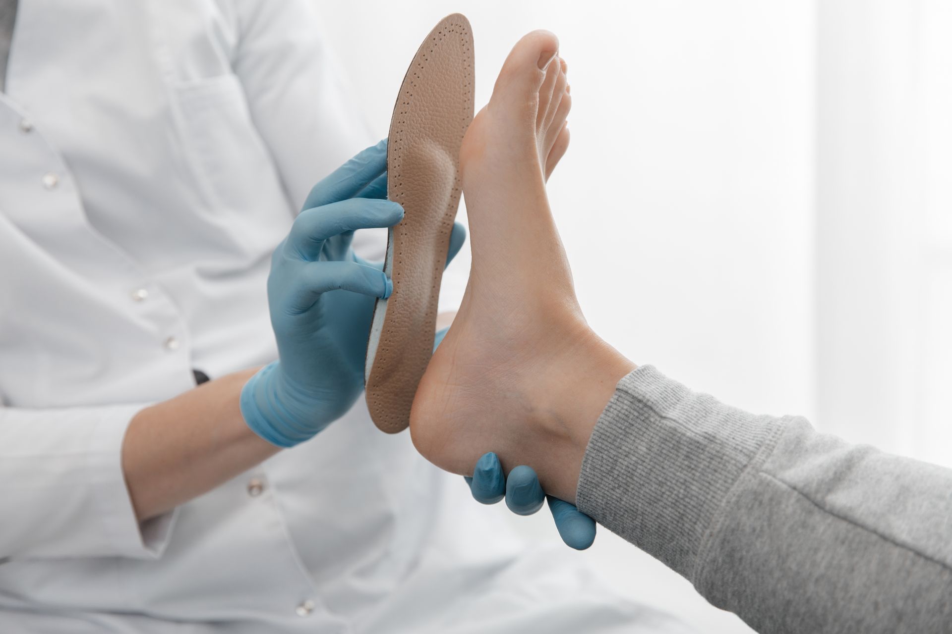 A doctor is examining a patient 's foot with a pair of insoles.