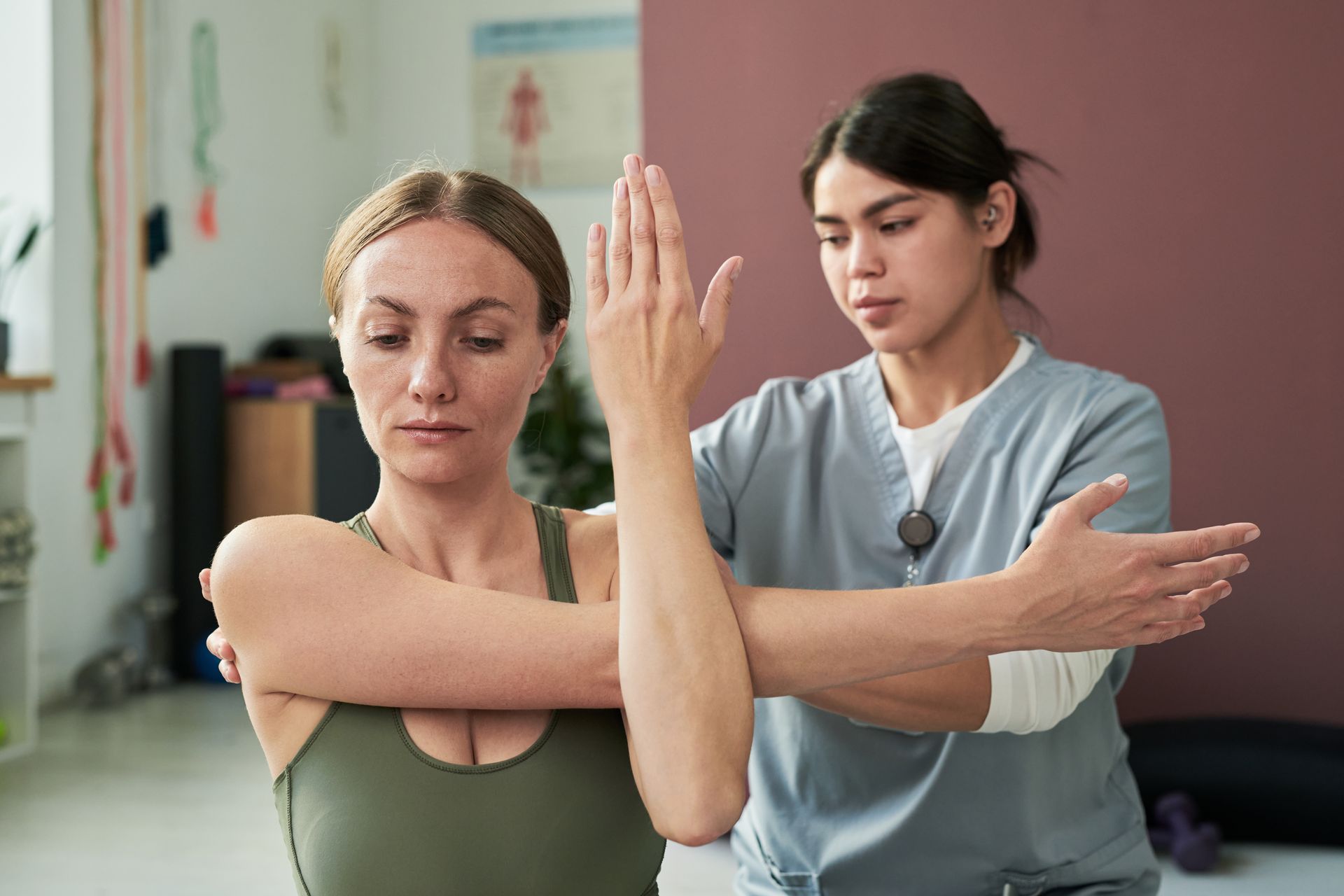 Woman being assisted by a therapist with arm stretching in a physical therapy session.