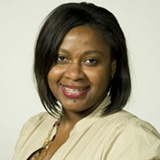 A woman in a tan shirt is smiling for the camera.