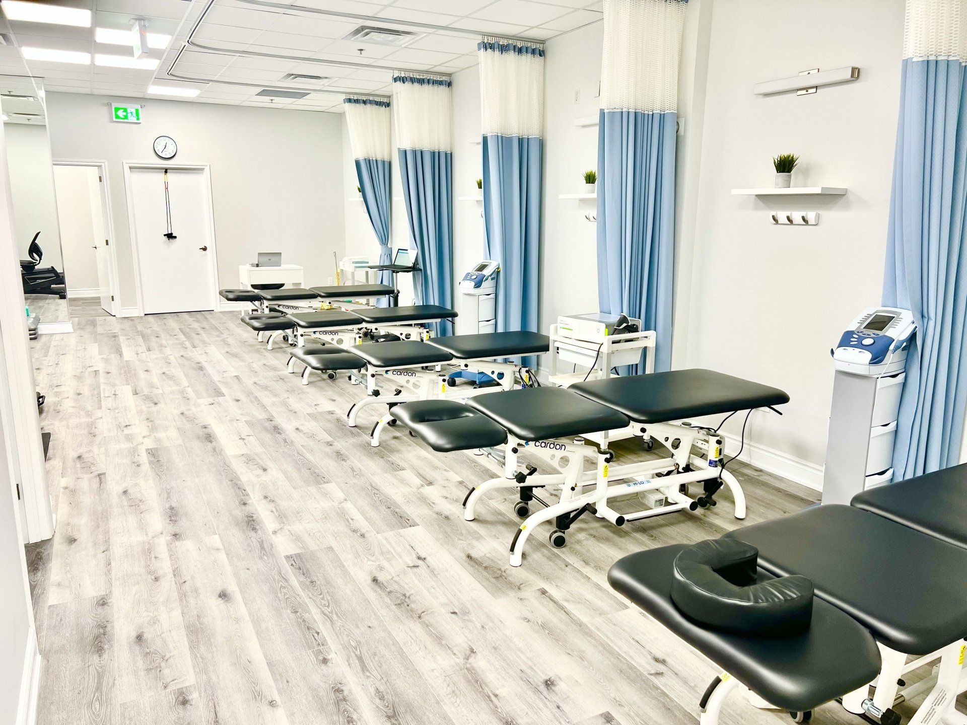 A row of physical therapy tables in a room with blue curtains.