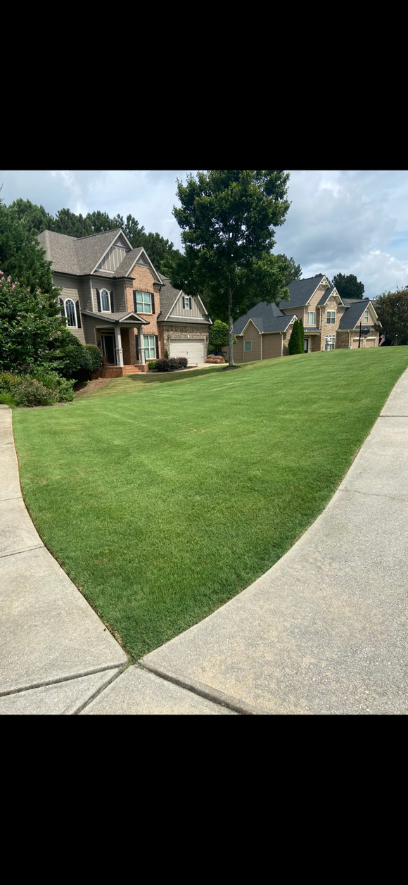 Roll of sod being unrolled onto green grass.