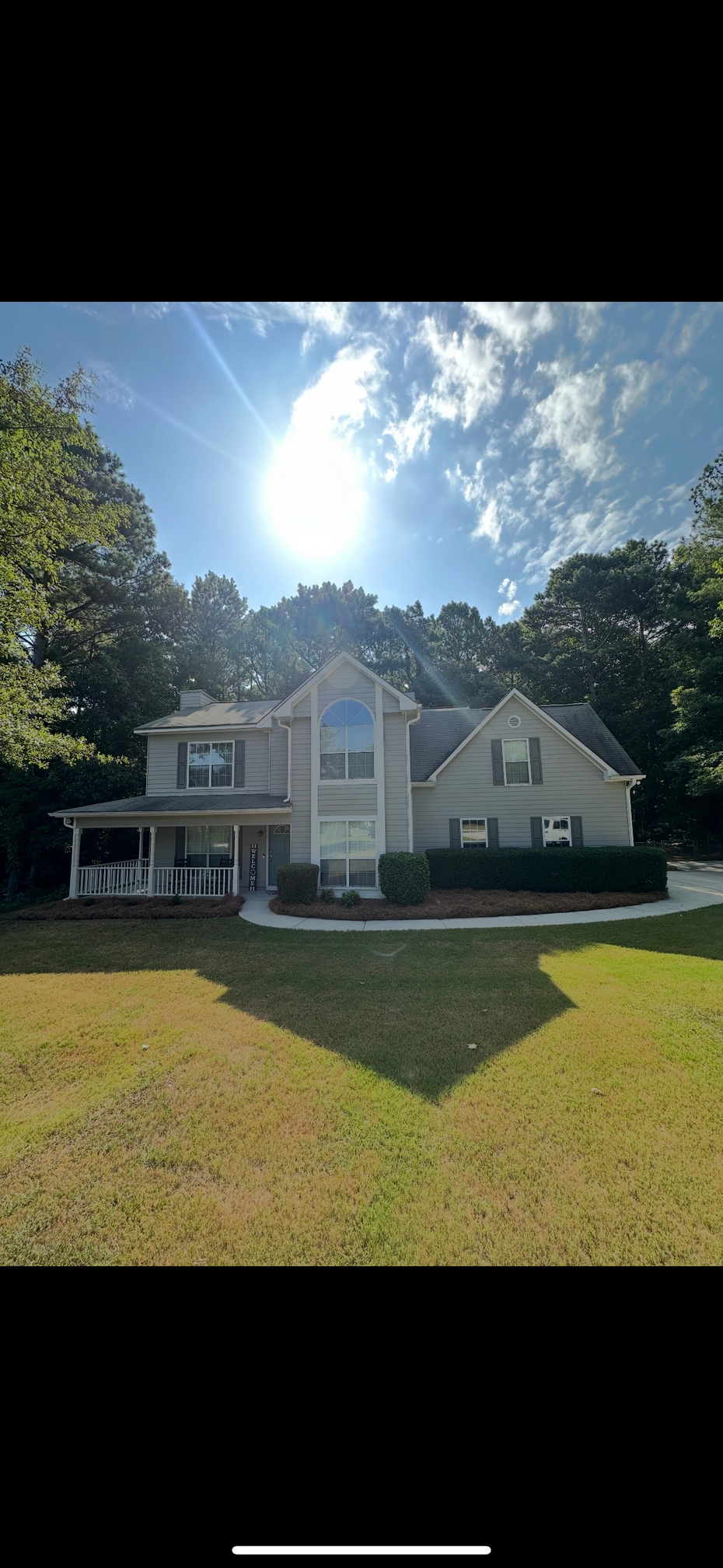 Brick house with manicured lawn and trees under a clear, blue sky.