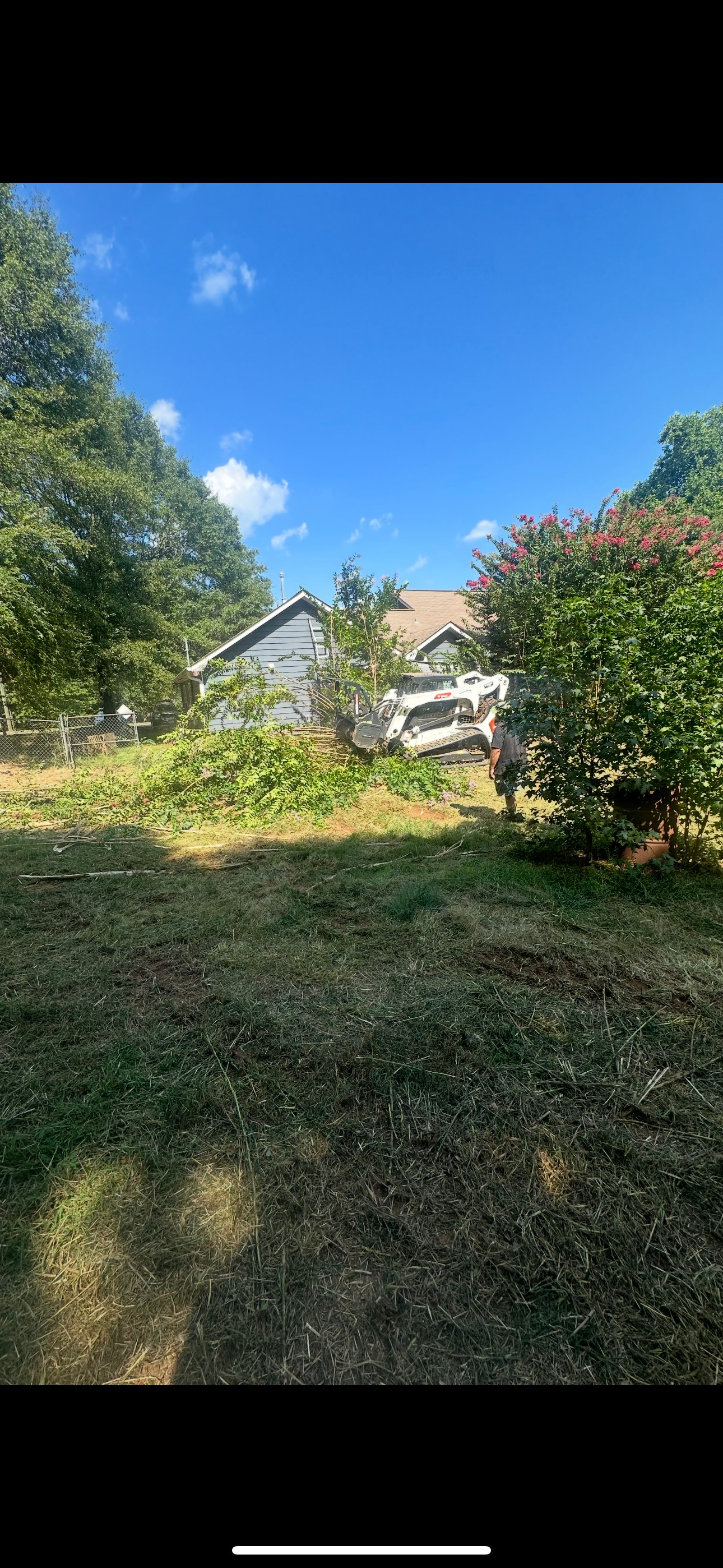 Brick house with long driveway, mailbox, and lush green lawn under a partly cloudy sky.