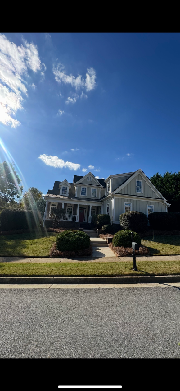 Hands using green shears to trim a green bush outdoors.