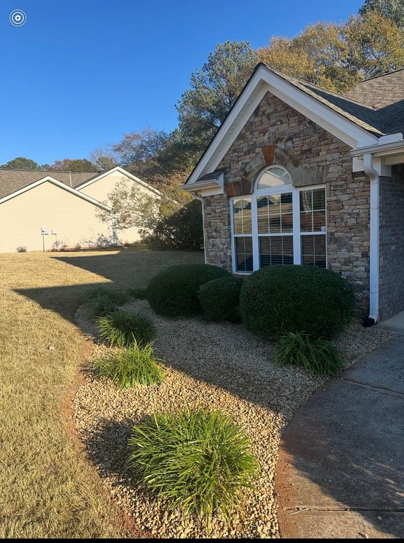 Person on roof installing solar panels on a gray house under a blue sky.