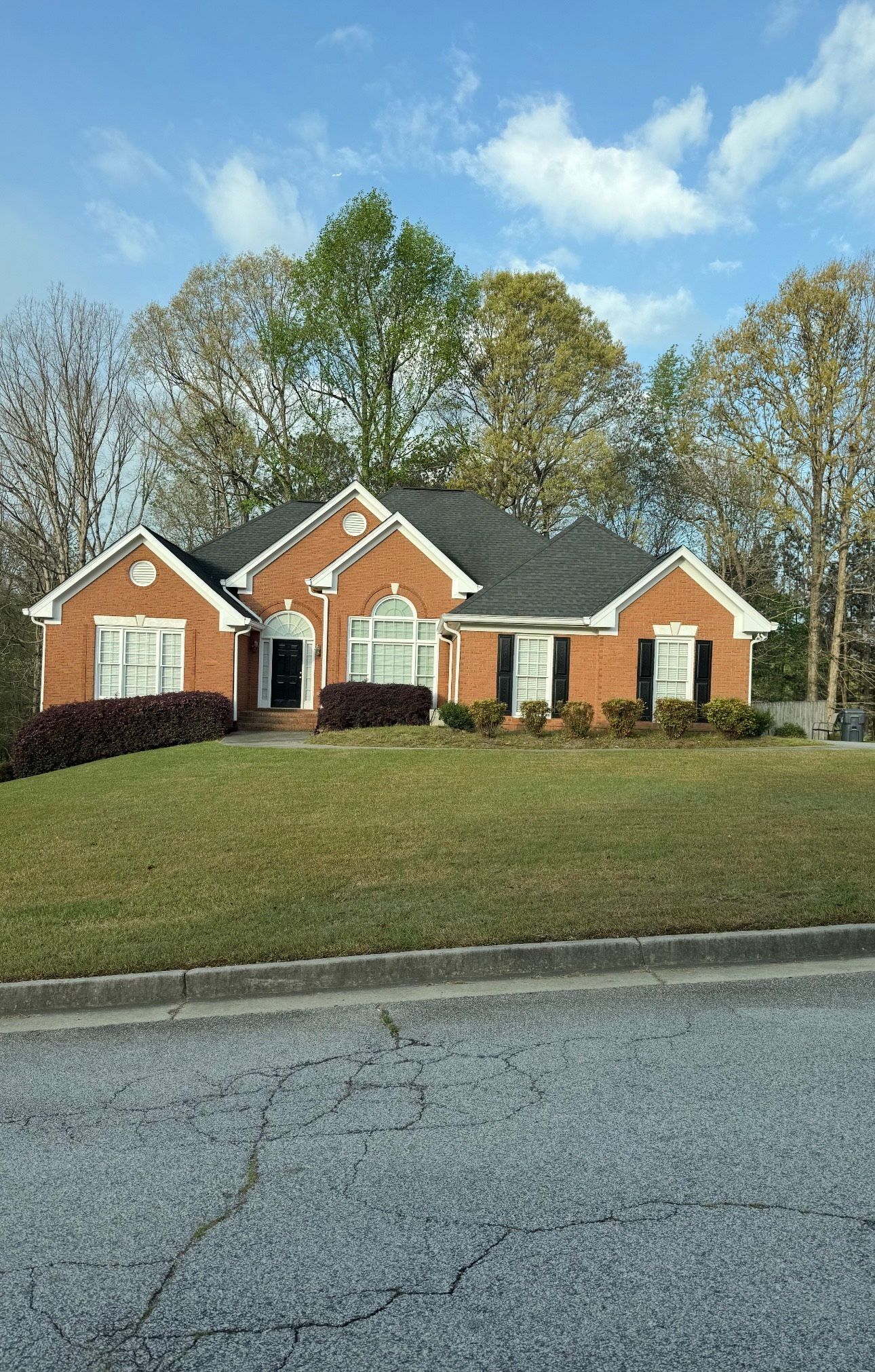 A person in red walks in a yard undergoing landscaping, with mulch, sod, and trees in the background.