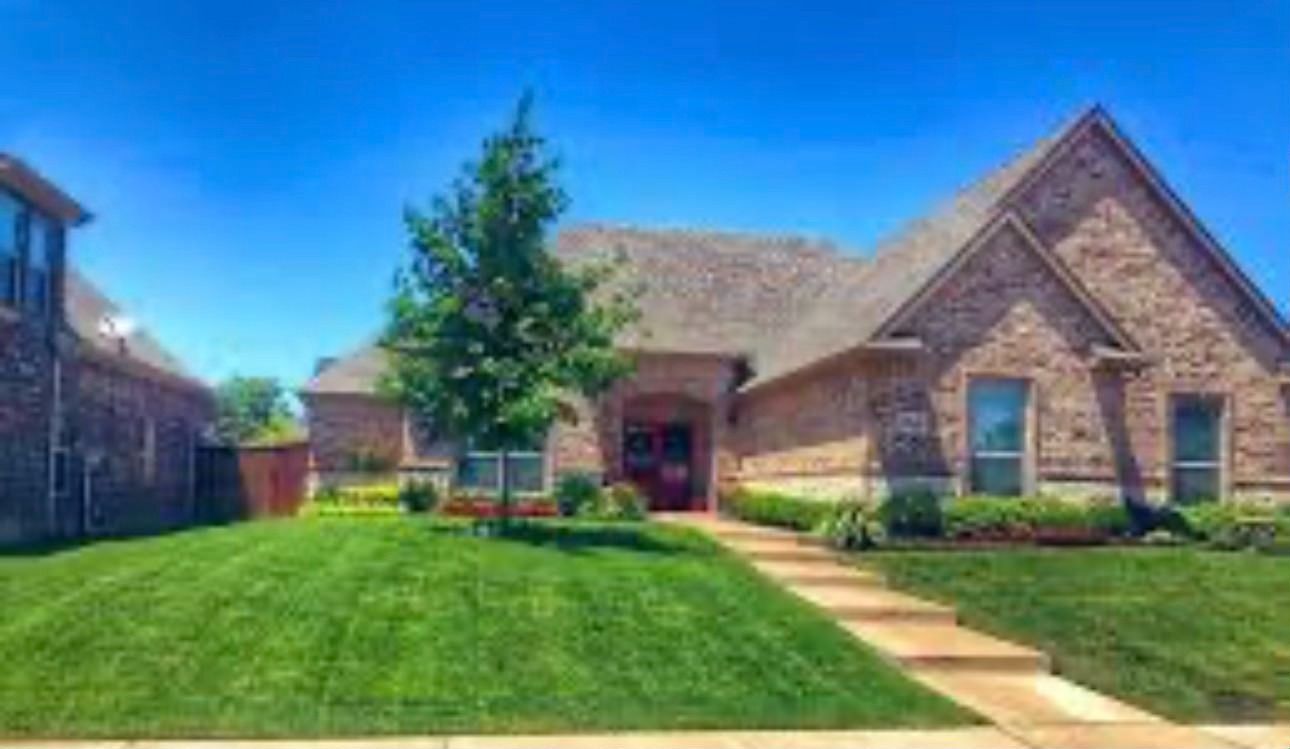 Brick house with green lawn and blue sky.