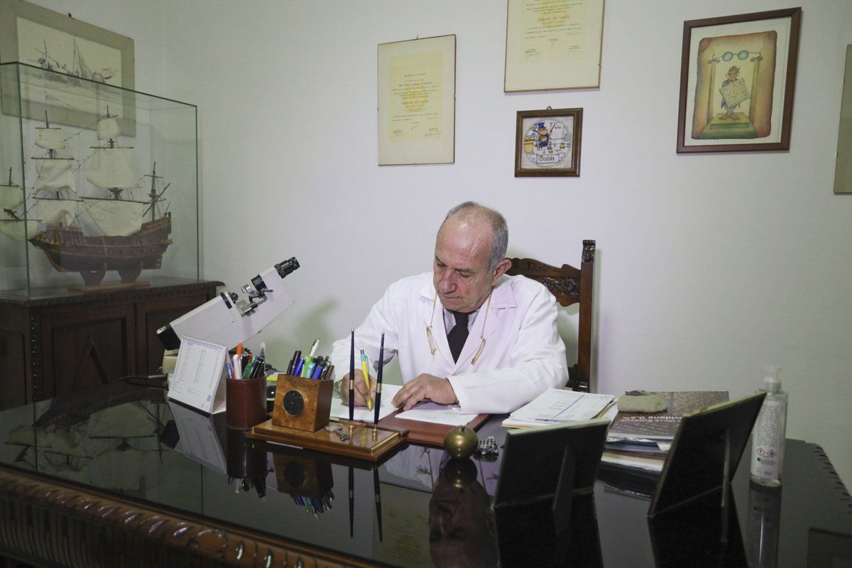 Un uomo in camice è seduto a una scrivania davanti a un microscopio.