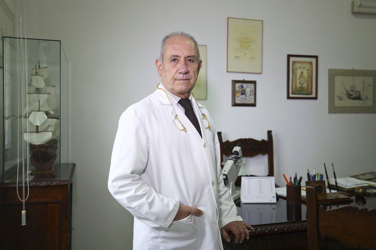 Un uomo con un camice bianco è in piedi davanti a una scrivania.