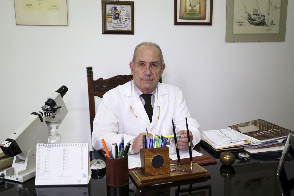 Un uomo in camice è seduto a una scrivania con un microscopio