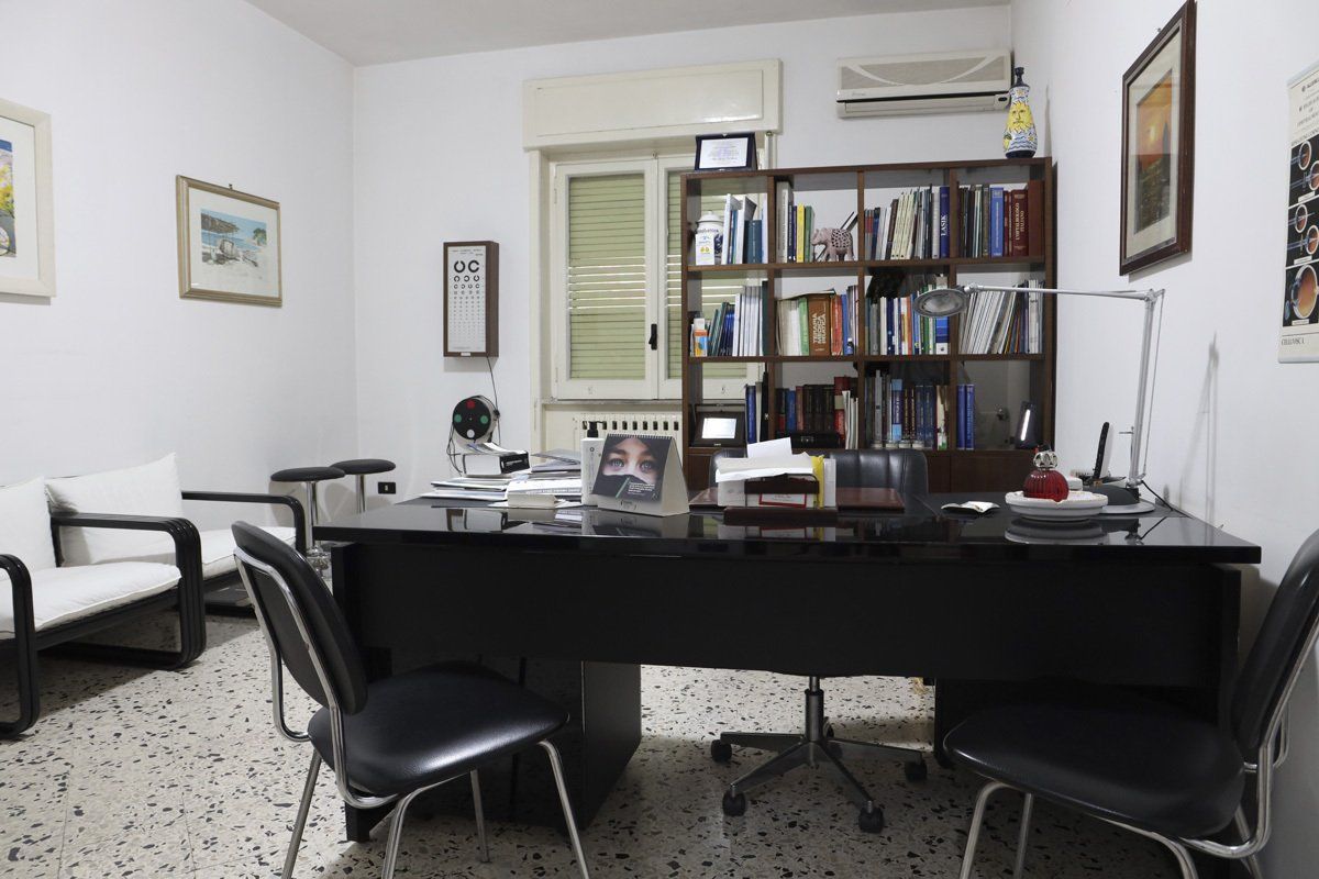 Una stanza con una scrivania e delle sedie e una libreria piena di libri