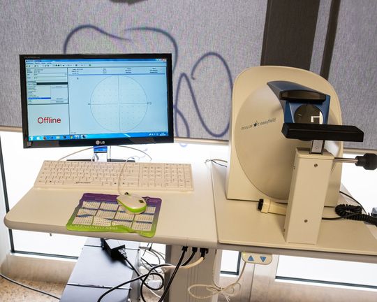 Una postazione di lavoro informatica con un monitor che visualizza un pattern di test circolare e un dispositivo ottico diagnostico specializzato.