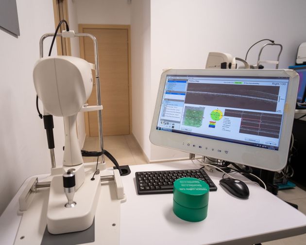 Apparecchiatura oftalmologica composta da uno scanner e un monitor che visualizza i dati diagnostici oculari su una scrivania bianca.