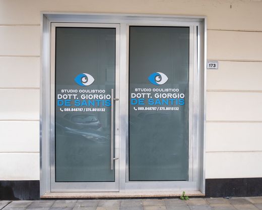 Porte a vetri per la clinica oculistica del Dott. Giorgio De Santis, con icone a forma di occhio blu e testo bianco e blu.