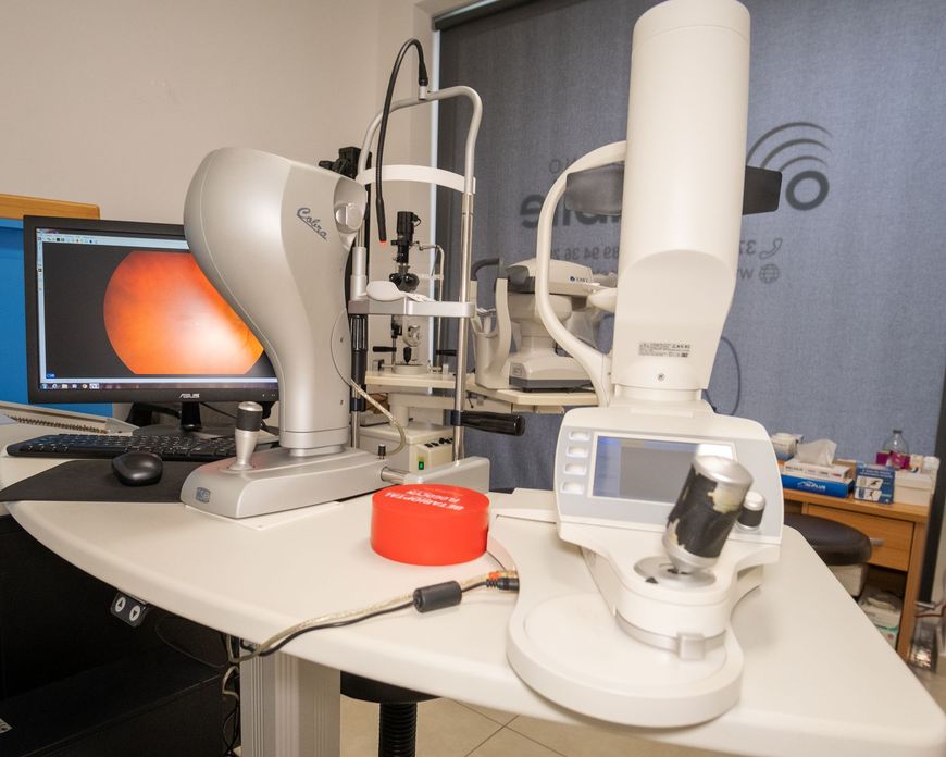 Sala per visite oftalmologiche dotata di telecamera retinica, lampada a fessura e monitor che visualizza l'immagine dell'esame oculare.