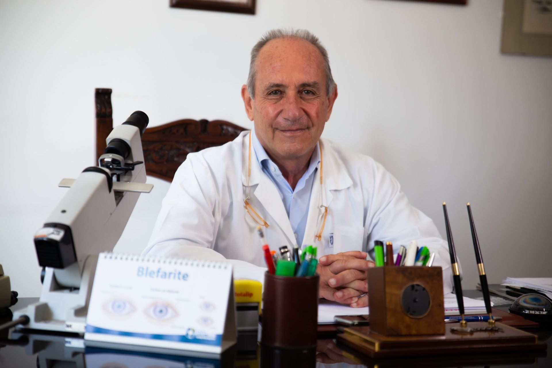 Un uomo in camice è seduto a una scrivania davanti a un microscopio.