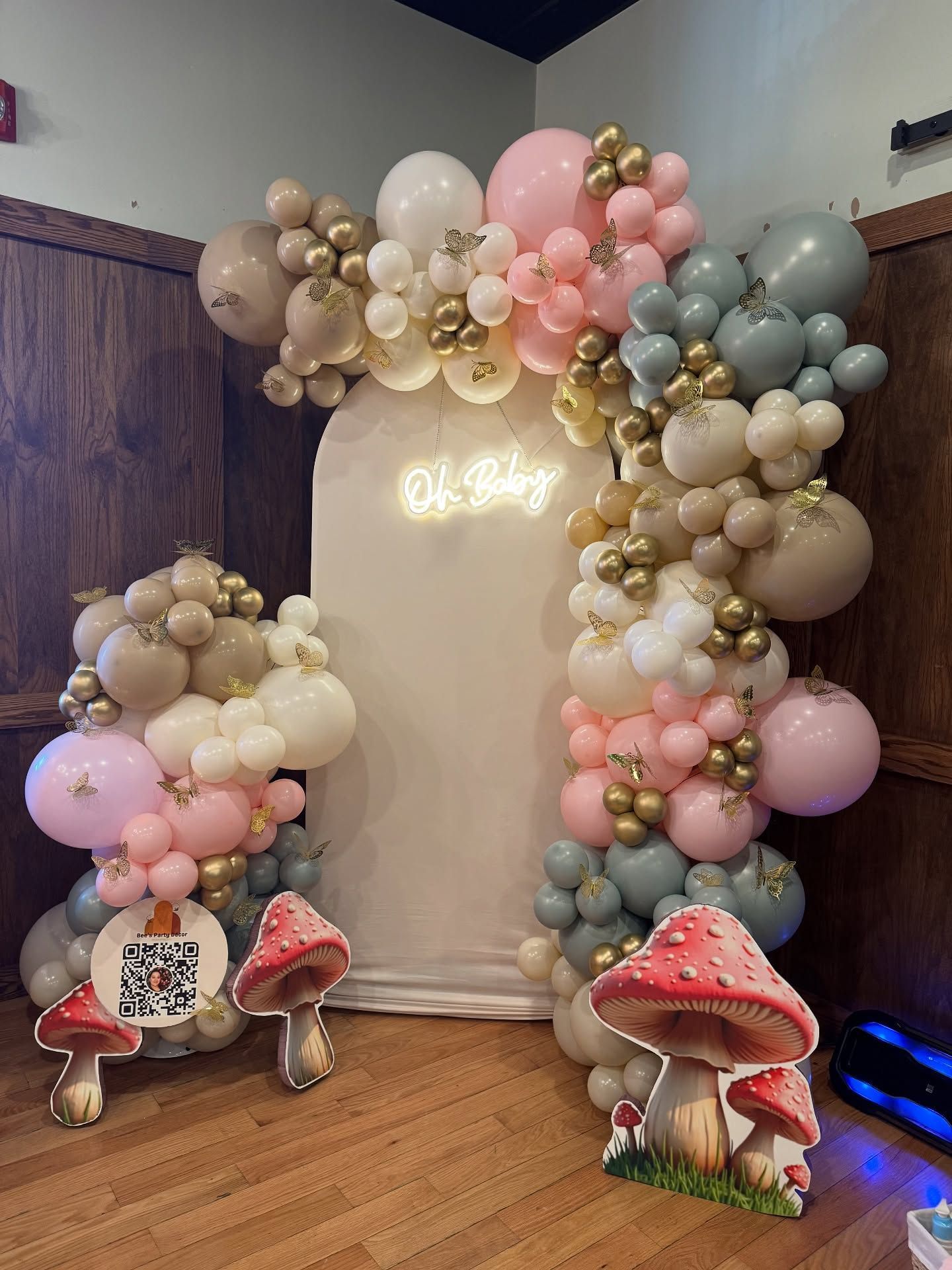 Pastel balloon arch with mushrooms framing a white backdrop in a corner room