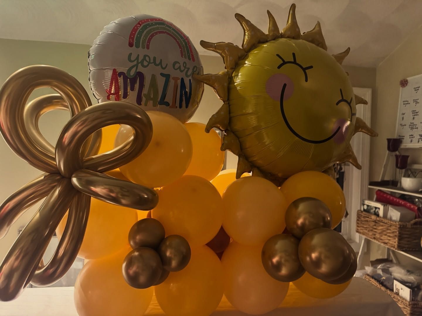 Gold and yellow balloon birthday display with a smiling sun and 